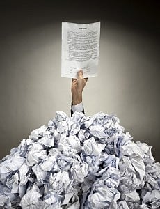 Hand with Agreement reaches out from big heap of crumpled papers